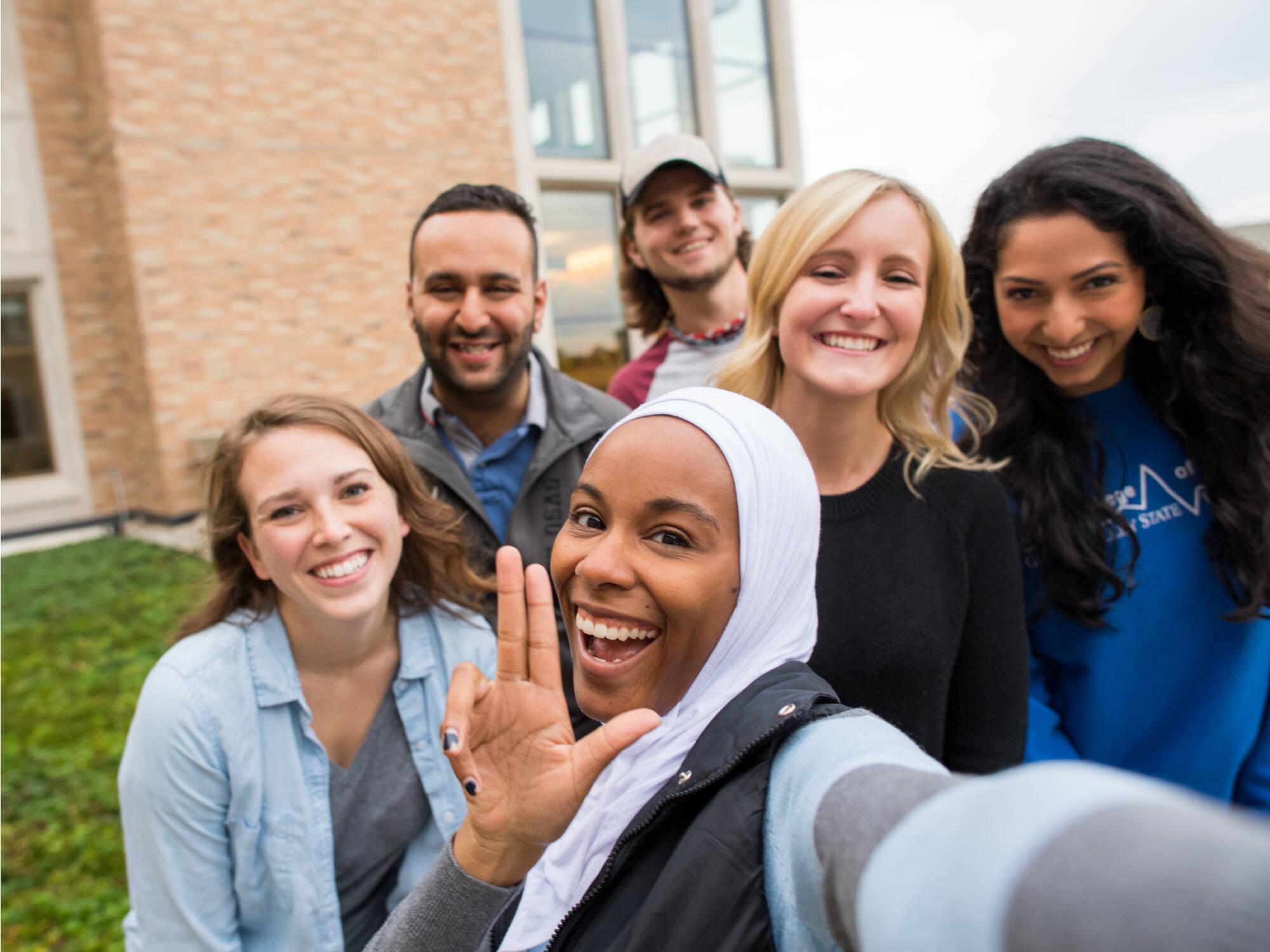 Selfie of six students in front of Seidman with one holding up an "L" with their fingers